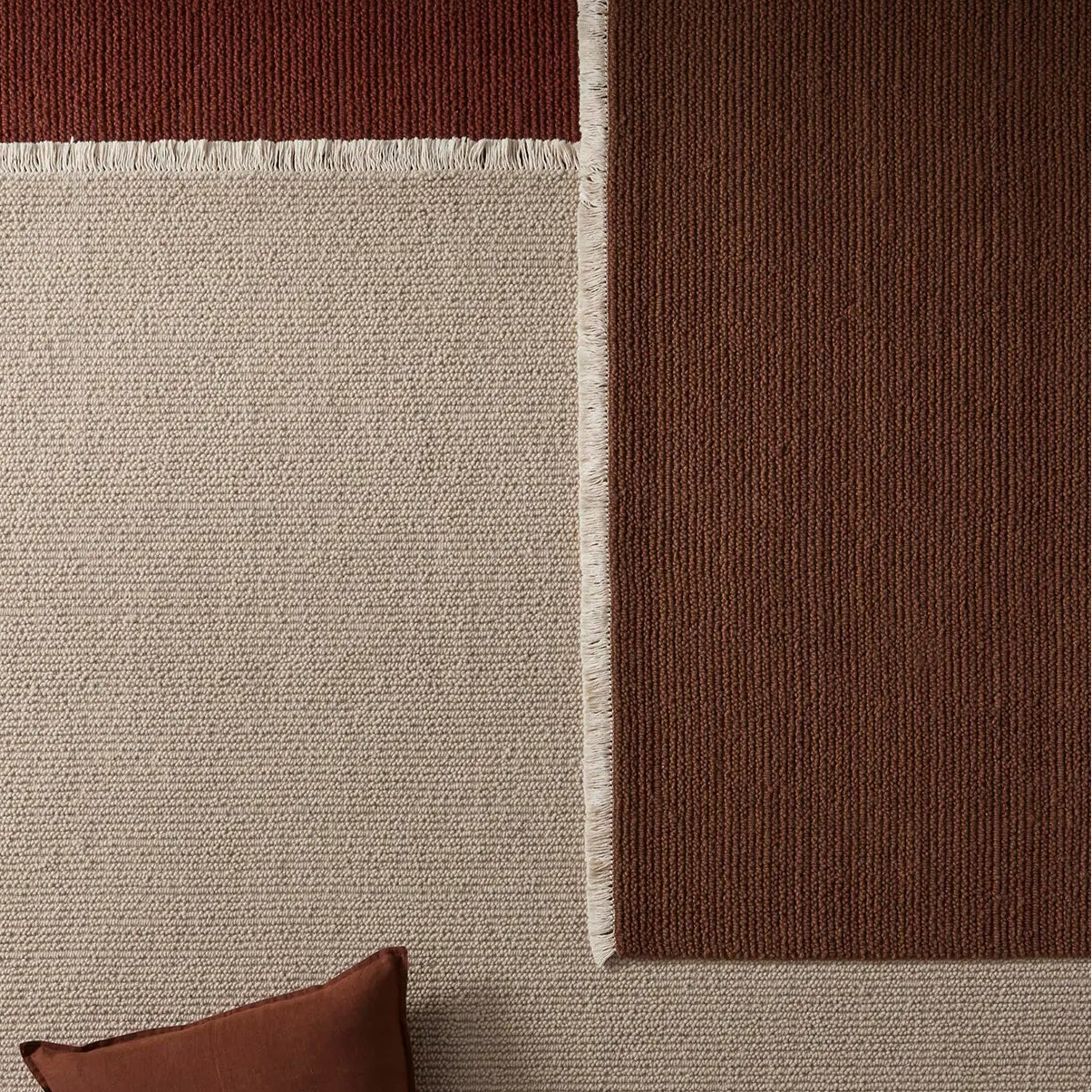 Beige rug with two brown cushions on a brown floor.