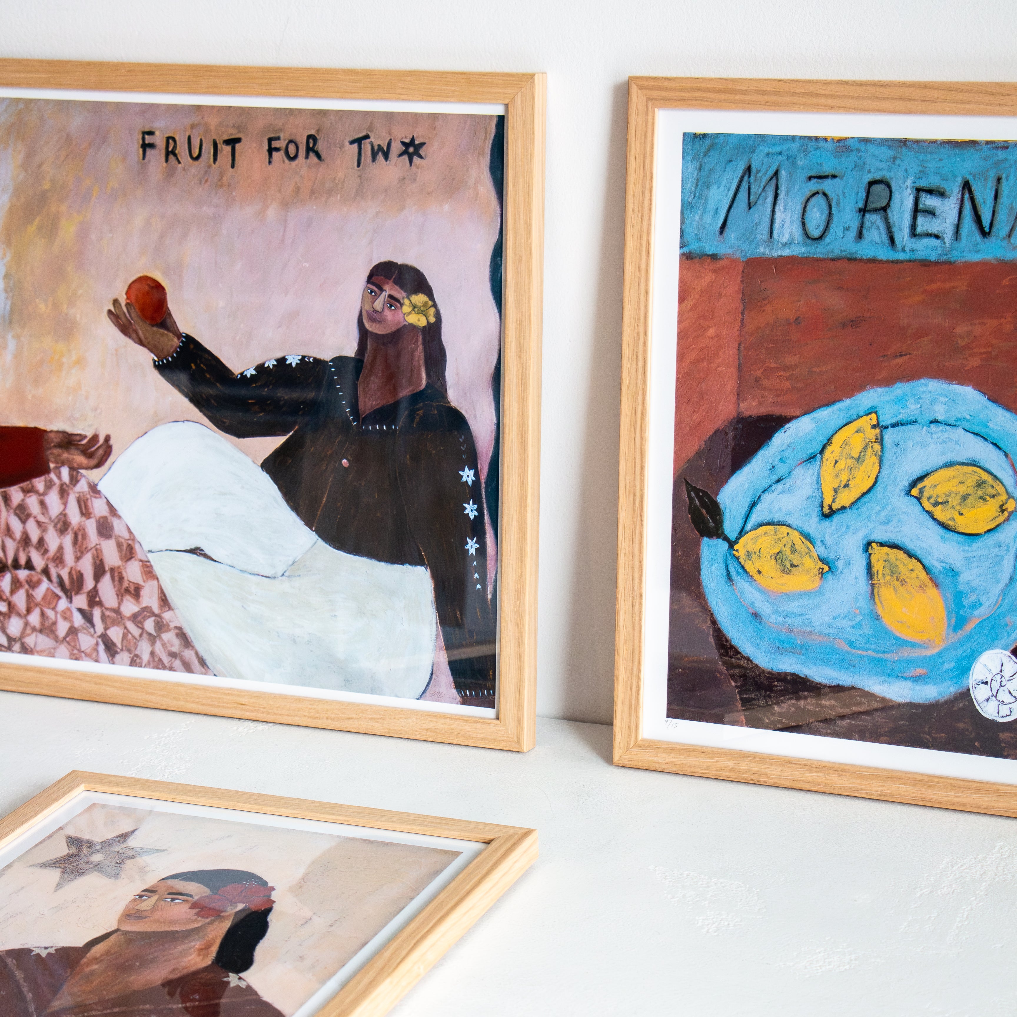 Three framed artworks on a white wall.