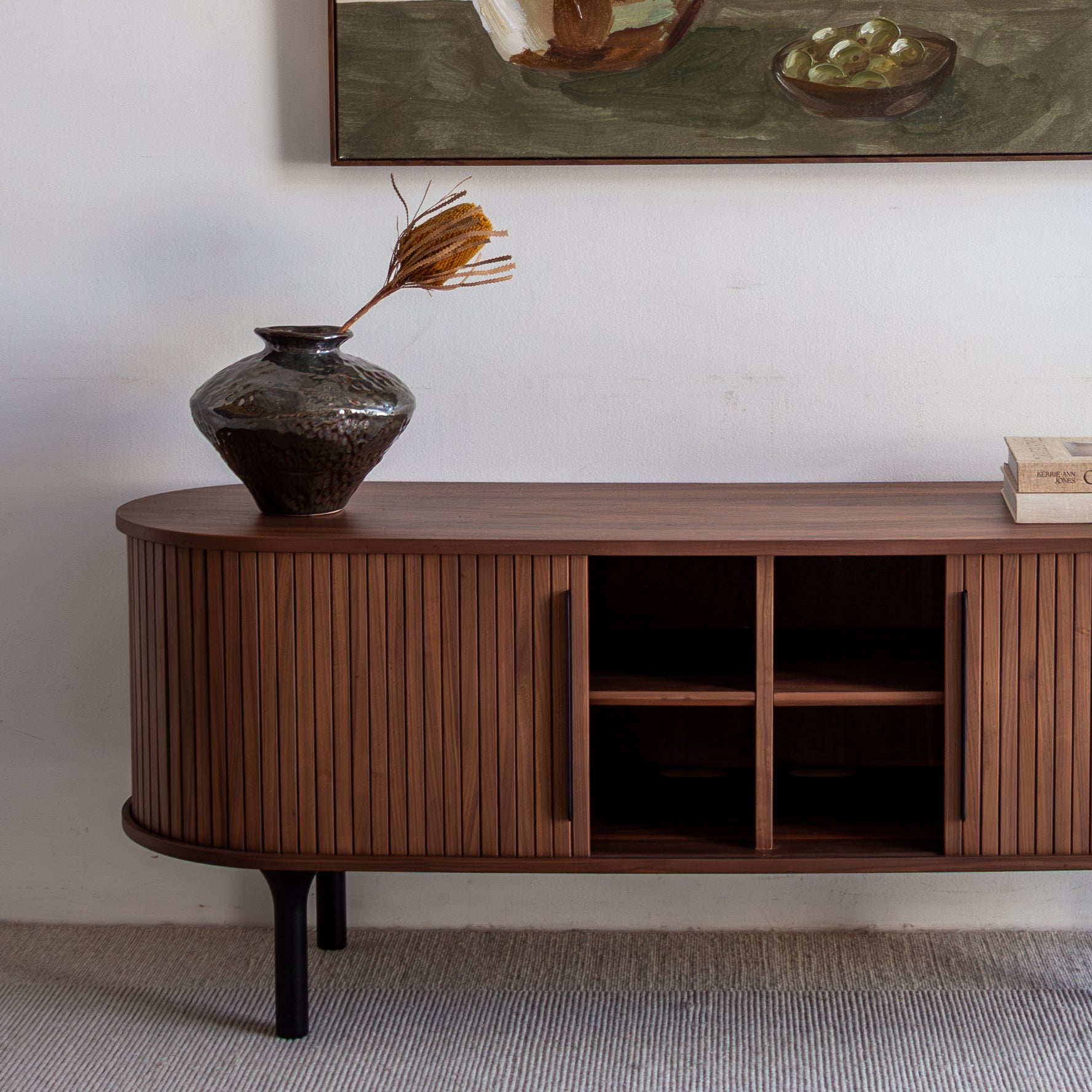 Wooden sideboard with a vase and books in a room setting