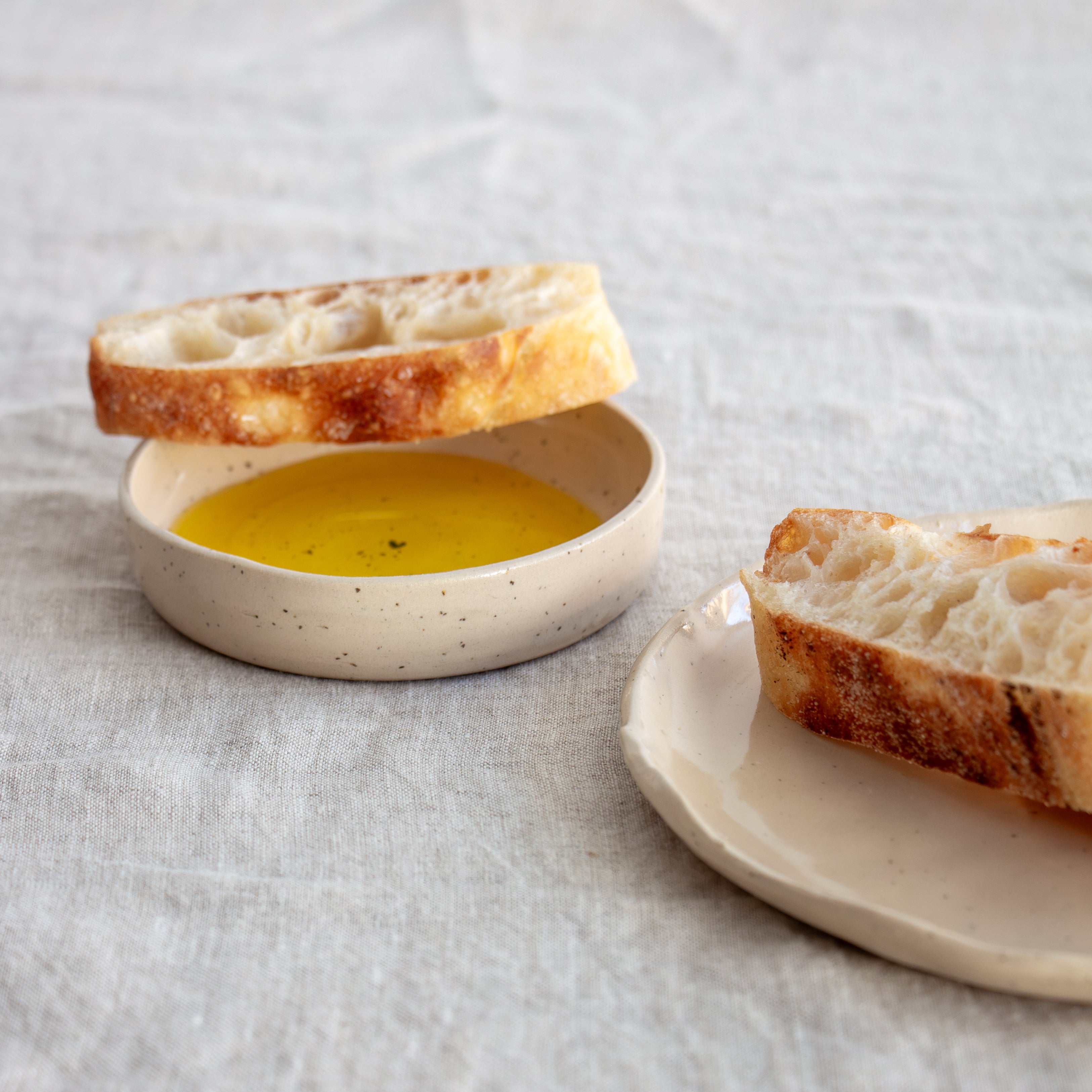 Bread slices with a small dish of oil on a textured surface