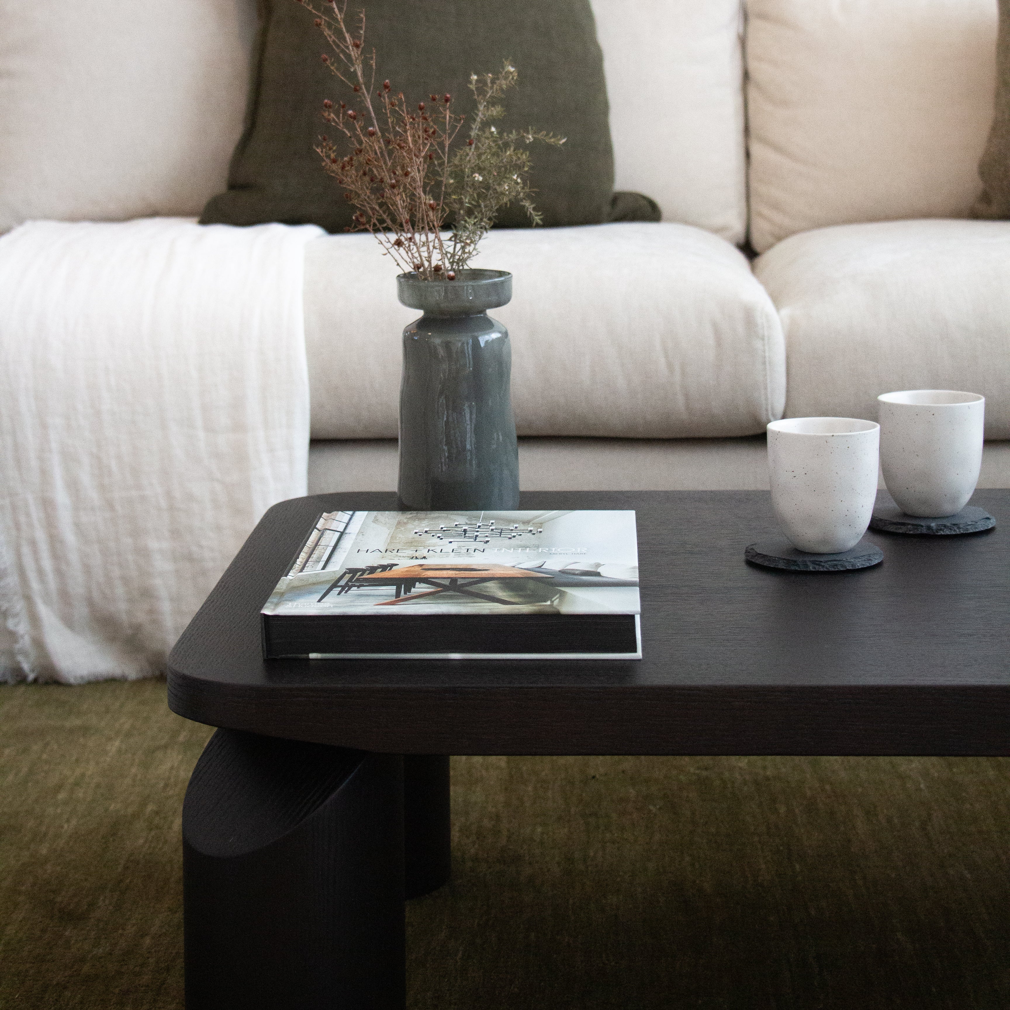 Coffee table with a book, vase, and two cups in a living room setting.