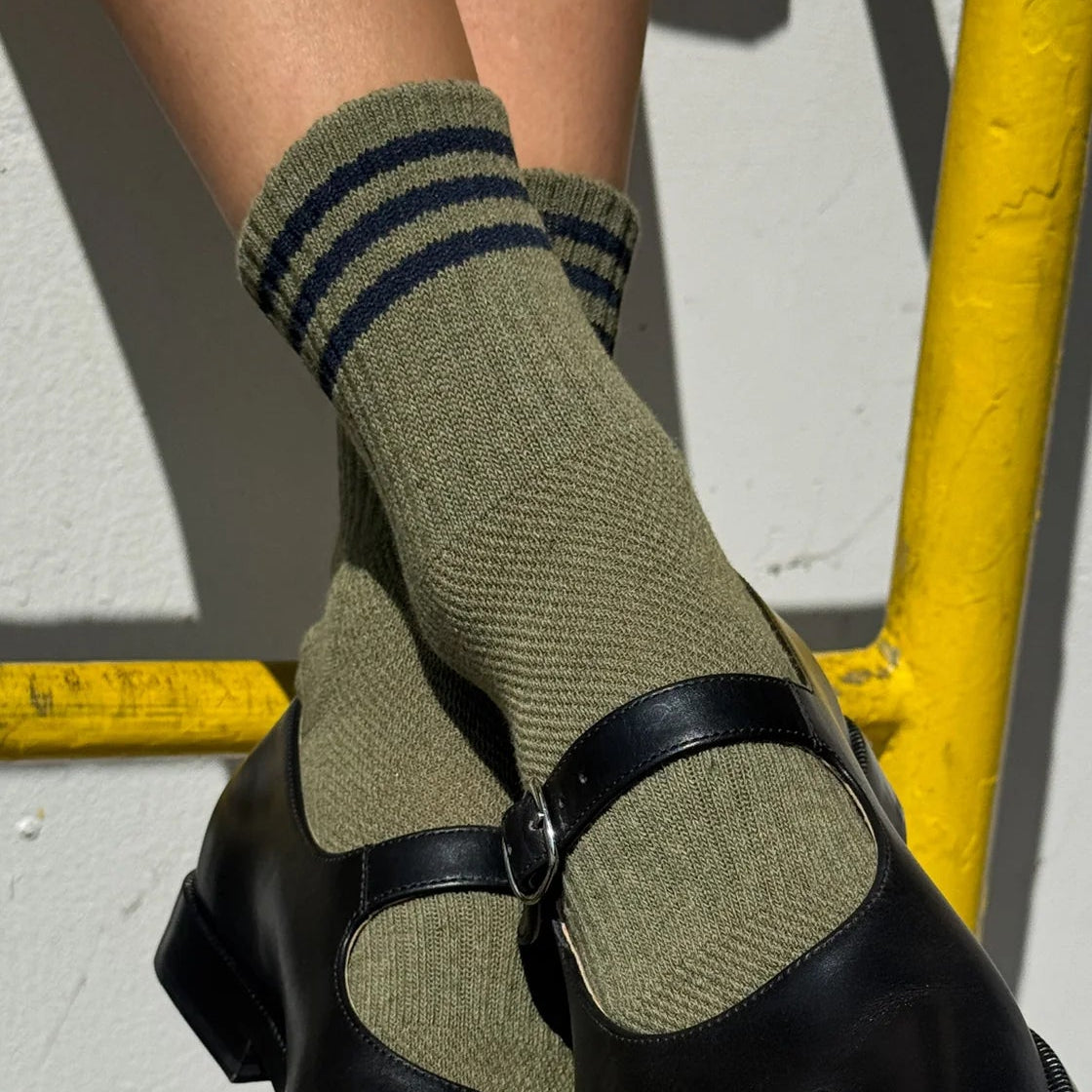 Black shoes with green socks and black straps on a yellow and gray background