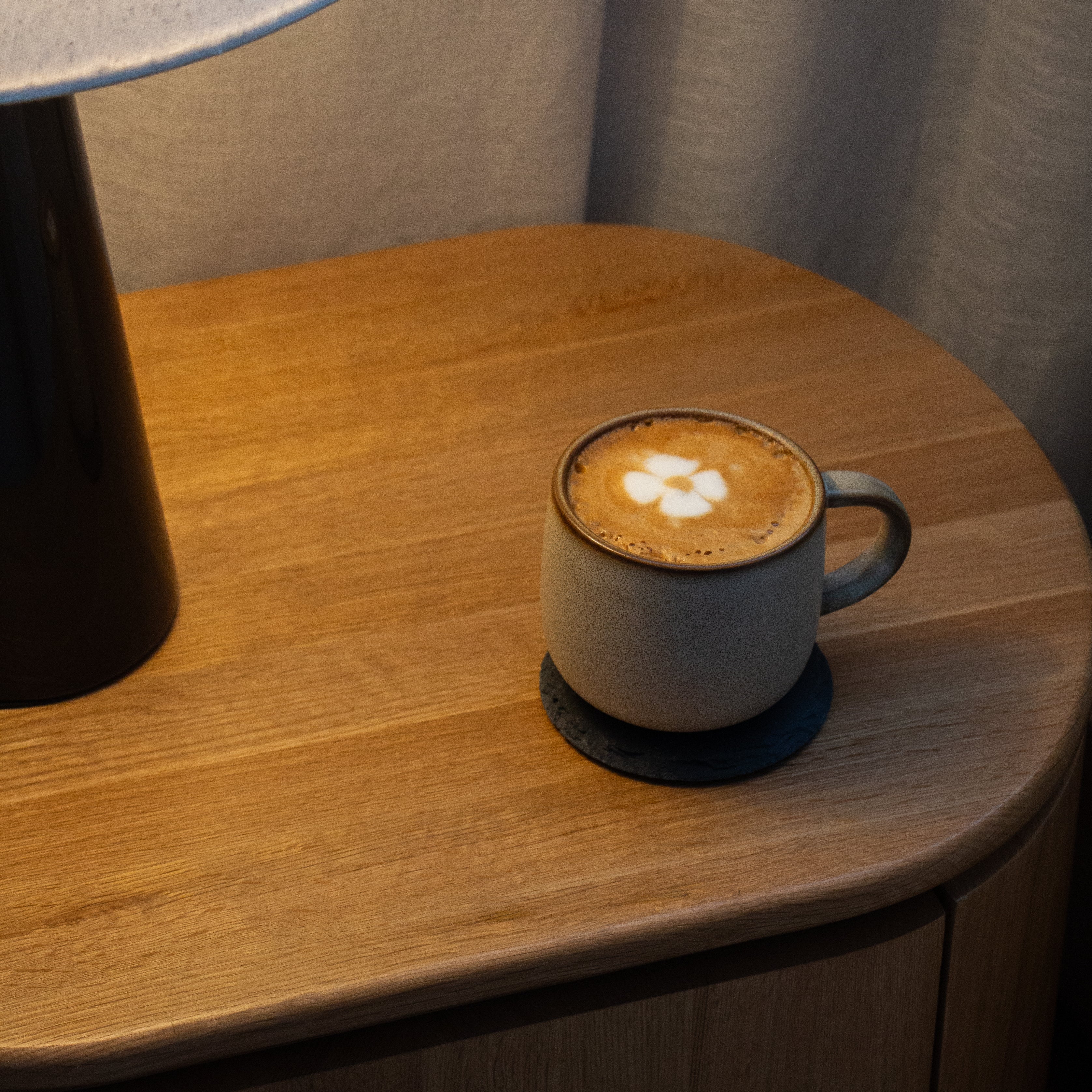 Cappuccino in a ceramic cup on a wooden table with a soft light in the background