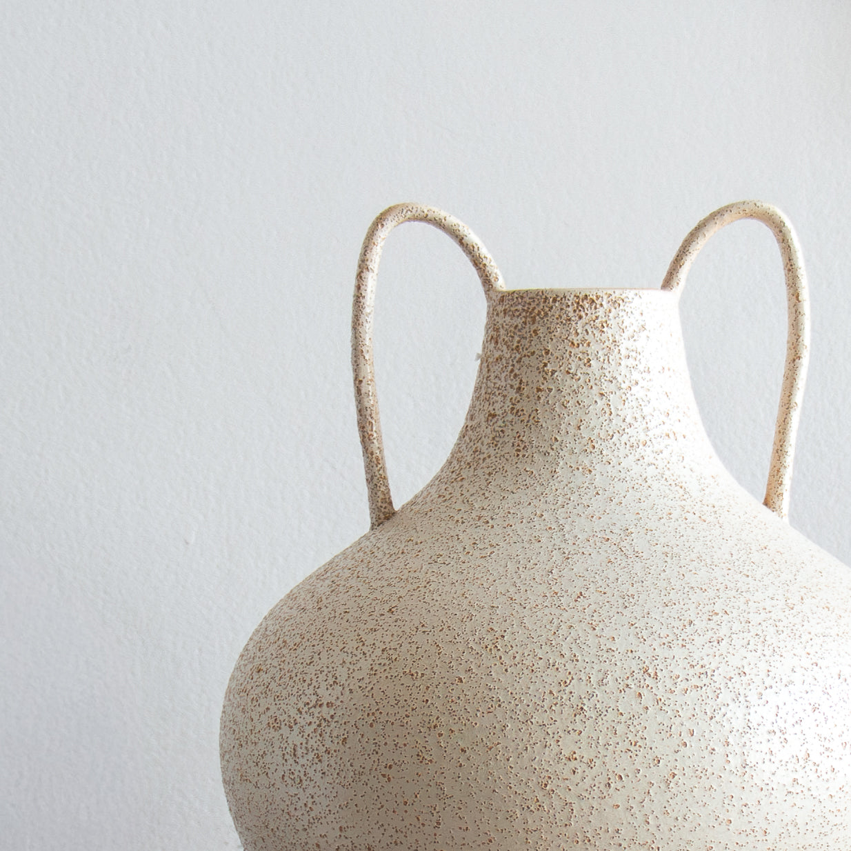 White ceramic vase with handles on a light gray background