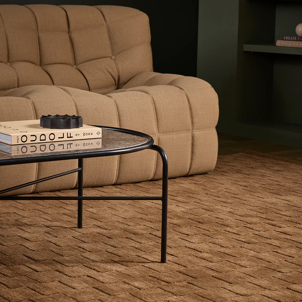 Beige recliner sofa in a living room with a coffee table and books.